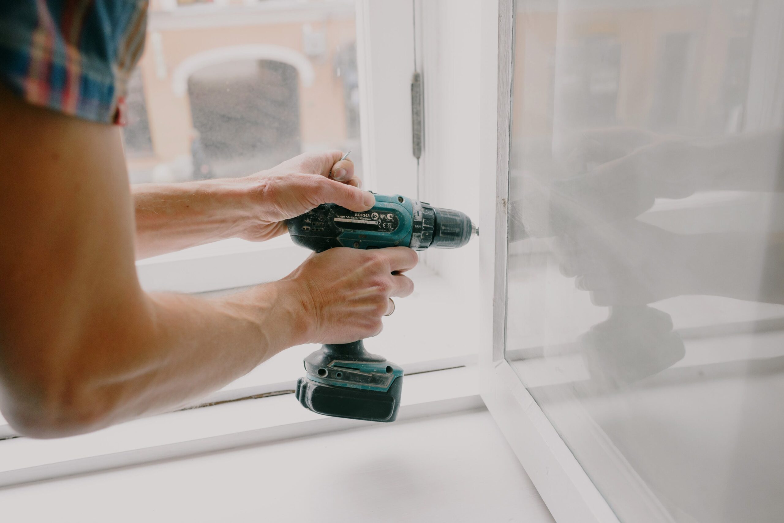 a person using a drill on a window frame